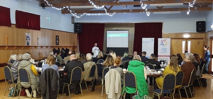 A photograph of a group of people watching a presentation on community justice.