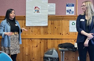 Two people standing in a room giving a presentation.