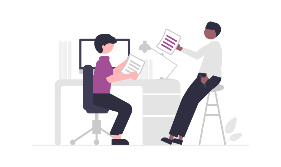 Two people sitting at a desk in front of a computer holding documents